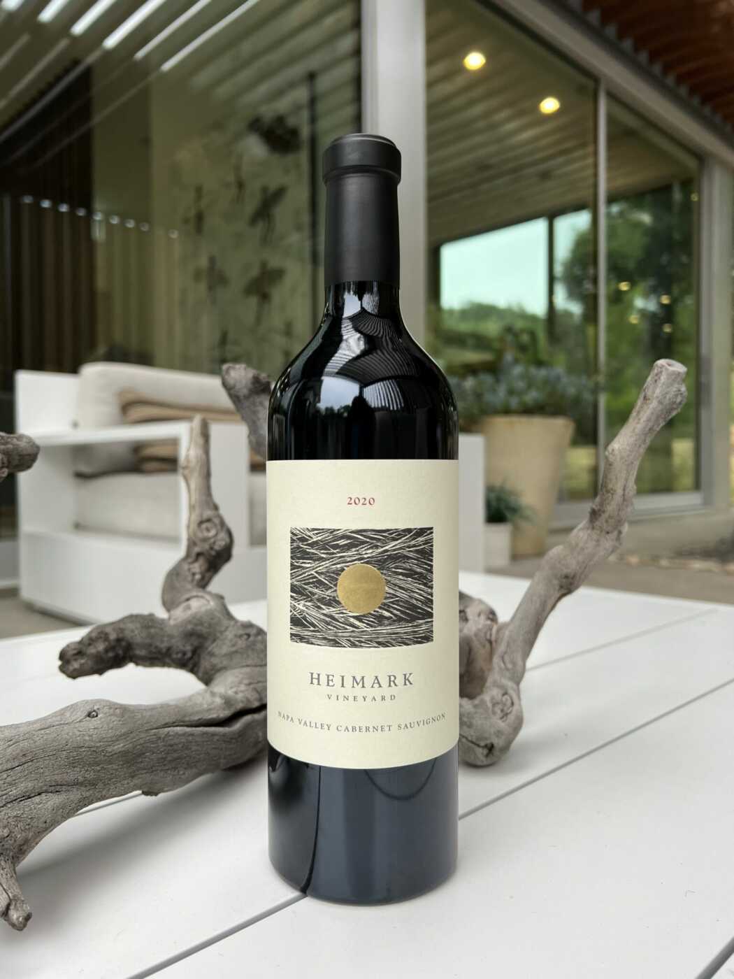 Heimark 2020 Cabernet Sauvignon on table in front of a tree branch